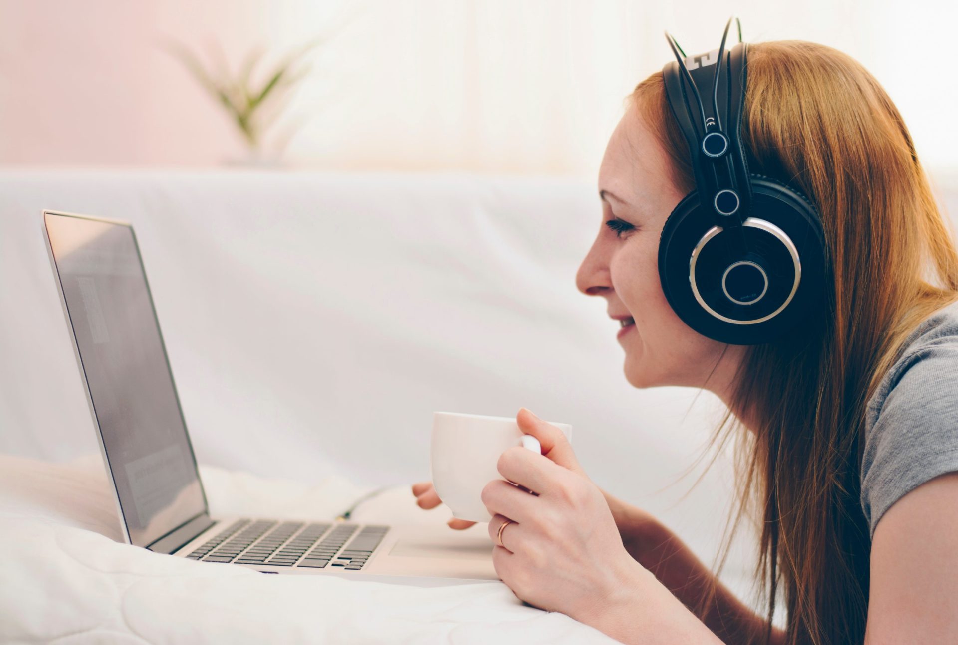 Lady on computer with headphones and tea during social isolation