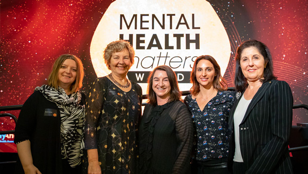 Jewish Care staff staning in front of the Mental health Matters logo