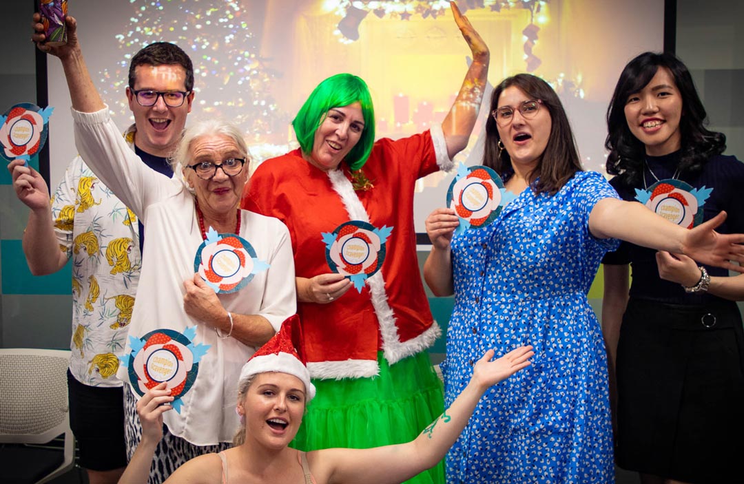 6 excited staff winning a rosette at the xmas party, one dressed as a female Grinch